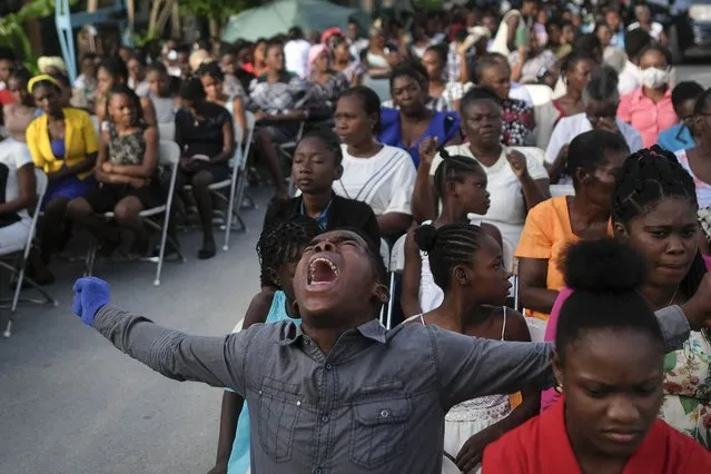 A parishioner shouts “Hallelujah” during a mass on the grounds next to an earthquake-damaged church in Les Cayes, Haiti, Sunday, August 22, 2021. (Photo by Matias Delacroix/AP Photo)