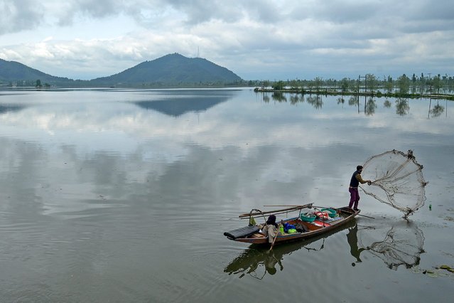 A fisherman casts his net from a boat at Dal Lake after water levels rose due to heavy rains, in Srinagar on April 30, 2024. (Photo by Tauseef Mustafa/AFP Photo)