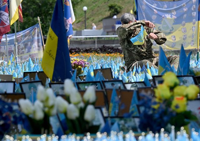 Ukrainian serviceman reacts as he sets a flag in a makeshift memorial for fallen Ukrainian soldiers at the Independence Square in Kyiv, on July 26, 2024, amid Russian invasion in Ukraine. (Photo by Sergei Supinsky/AFP Photo)