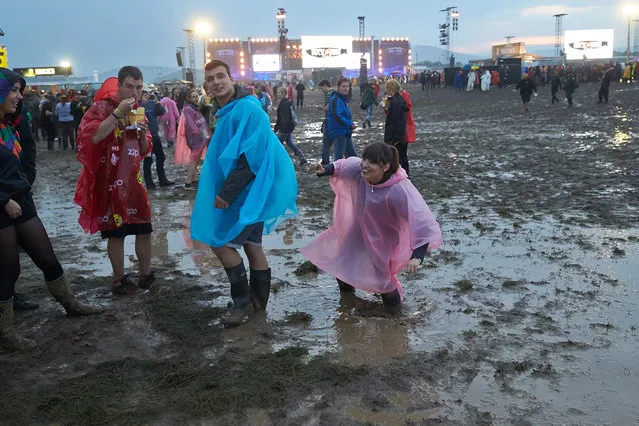 In this Friday June 3, 2016 picture people walk  through the mud  after a thunderstorm hit the open air music festival “Rock am Ring”  in Mendig, Germany. Several people were hospitalized after lightning struck the rock festival in western Germany on Friday police said, the second straight year lightning has injured fans at the Rock am Ring festival. Organizers have suspended  the rock festival in western Germany Sturday June 4, 2016.   (Photo by Thomas Frey/DPA via AP Photo)