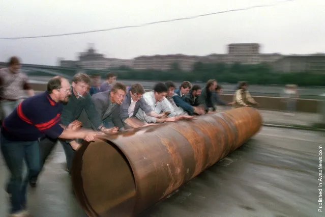 Supporters of Russian president Yeltsin roll a large metal pipe to use as a barricade near the Russian federation building in Moscow, on August 19, 1991, following a military coup attempt by Soviet hardliners