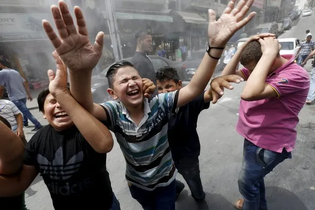 Children react as personnel from the Greater Amman Municipality spray them with a water sprinkler in order to cool them down, as part of measures to ease the effect of a heatwave, in Amman, Jordan August 3, 2015. (Photo by Muhammad Hamed/Reuters)