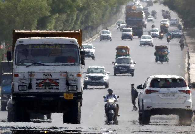 Traffic moves on a road in a heat haze during hot weather on the outskirts of Ahmedabad, India, May 12, 2022. (Photo by Amit Dave/Reuters)