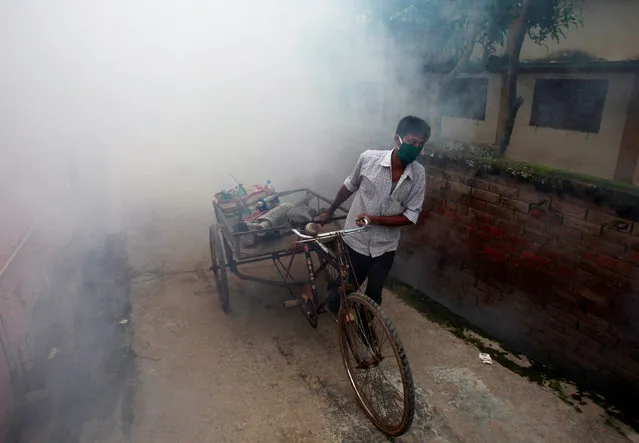 A municipal worker fumigates a residential colony in Agartala, India, June 13, 2016. (Photo by Jayanta Dey/Reuters)