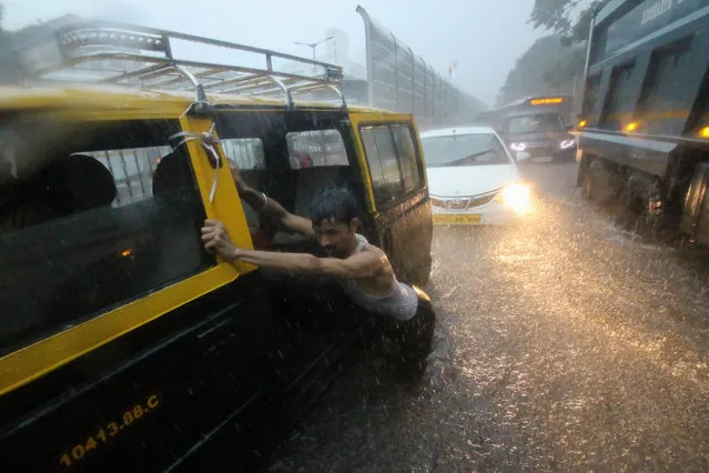 A man pushes a taxi through a waterlogged street during heavy rains in Mumbai, India on 01 July 2019. Monsoon in India officially lasts from June to September. (Photo by Himanshu Bhatt/NurPhoto via Getty Images)