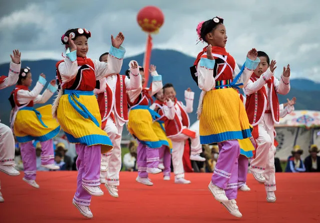 Children dance for spectators at a traditional horseracing festival in the Diqing Tibetan Autonomous Prefecture in south-west China on June 6, 2016. (Photo by Xinhua/Barcroft Images)