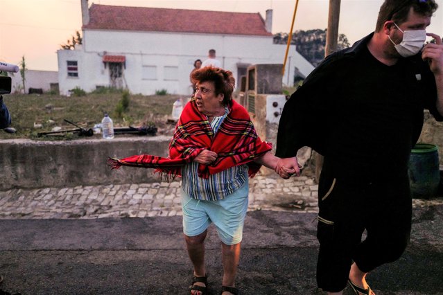 An elderly woman leaves her house as a wildfire approaches, in Cascais, Portugal on July 25, 2023. (Photo by Pedro Nunes/Reuters)