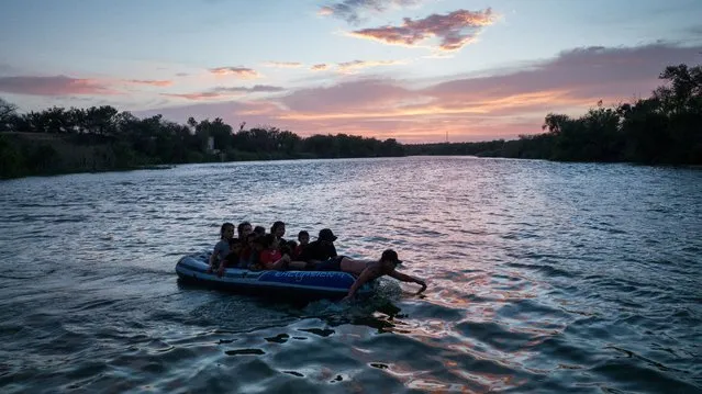 A smuggler uses his hands to paddle on a raft full of asylum seeking migrants from Central and South America across the Rio Grande river into the United States from Mexico in Roma, Texas, U.S., June 13, 2022. (Photo by Adrees Latif/Reuters)