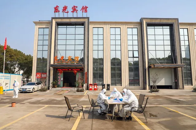 People in overalls talk at a table outside a hotel accommodating isolated people in Wuhan, Hubei province, China, 03 February 2020. (Photo by Yuan Zheng/EPA/EFE)
