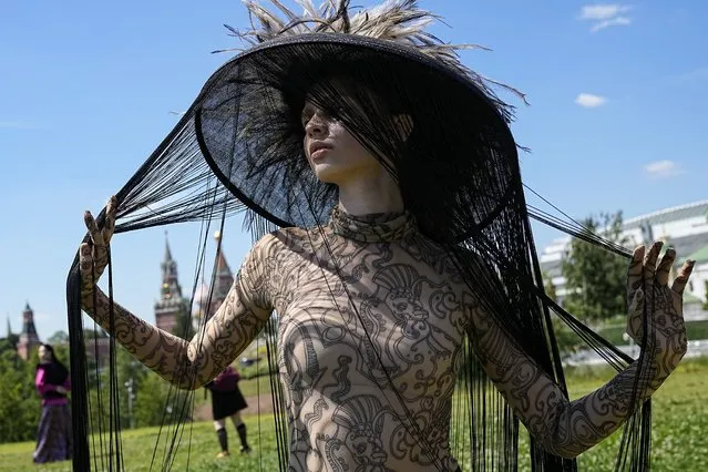 A model poses for photographers backstage after displaying a collection by graduates of the British Higher School of Art & Design during the Fashion Week at Zaryadye Park near Red Square in Moscow, Russia, Friday, June 24, 2022. (Photo by Alexander Zemlianichenko/AP Photo)