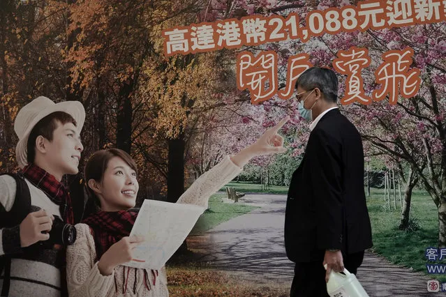 A man wearing a mask, walks past an advertisement for a bank in Hong Kong, Tuesday, February 18, 2020. Hong Kong leader Carrie Lam on Tuesday said there is uncertainty around the effort to repatriate some 350 Hong Kong citizens from a quarantined cruise ship docked in Yokohama, a port city near Tokyo. The ship has the largest number of cases of the new virus that emerged in China late last year. (Photo by Kin Cheung/AP Photo)