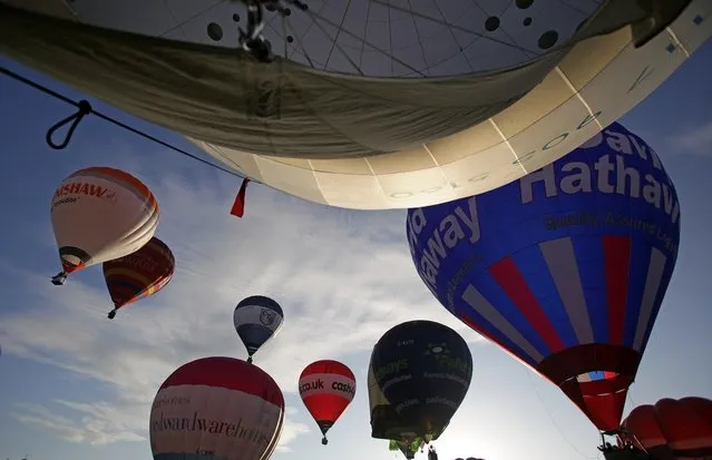 Hot air balloons take to the skies over Bristol city centre on August 6, 2012 in Bristol, England. The early morning flight of over twenty balloons over the city was organised as a curtain raiser for the four-day Bristol International Balloon Fiesta which starts on Thursday. Now in its 34th year, the Bristol International Balloon Fiesta is Europe's largest annual hot air balloon event in the city that is seen by many balloonists as the home of modern ballooning.  (Photo by Matt Cardy)