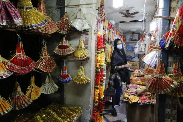 A Hindu woman wearing a mask shops for religious items on the eve of the Hindu festival Navratri in Prayagraj, India, Tuesday, March 24, 2020. Indian Prime Minister Narendra Modi Tuesday announced a total lockdown of the country of 1.3 billion people to contain the new coronavirus outbreak. For most people, the new coronavirus causes only mild or moderate symptoms. For some it can cause more severe illness. (Photo by Rajesh Kumar Singh/AP Photo)