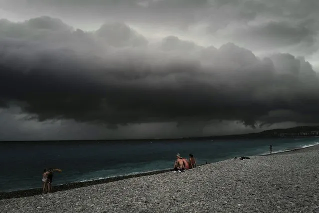 Beach-goers look at the clouds before a storm along the “Promenade des anglais” on the french riviera city of Nice, on June 28, 2022. (Photo by Valery Hache/AFP Photo)