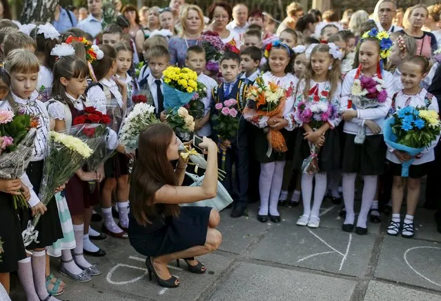 A woman takes pictures as first graders attend a ceremony to mark the start of another school year in Kiev, Ukraine, September 1, 2015. (Photo by Gleb Garanich/Reuters)