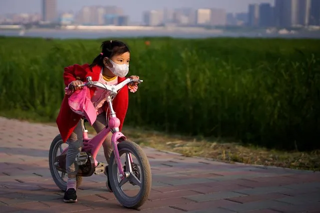 A girl wearing a face mask rides her bicycle at a park after the lockdown was lifted in Wuhan, capital of Hubei province and China's epicentre of the novel coronavirus disease (COVID-19) outbreak, April 12, 2020. (Photo by Aly Song/Reuters)