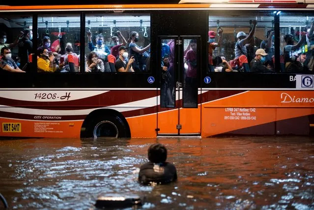 A child swims in the flood water caused by heavy rains as a passenger bus passes by, in Manila, Philippines on August 6, 2022. (Photo byLisa Marie David /Reuters)