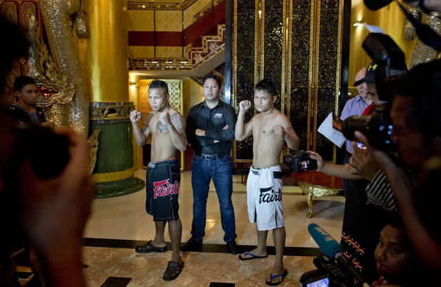 In this Friday, July 17, 2015, photo, Hlit Hlit Lay, right, a member of the White New Blood lethwei fighters club, a Myanmar traditional martial-arts club which practices a rough form of kickboxing, poses with opponent Tha Pyay Nyo, left and “One Championship” President Victor Cui, center, ahead of their featherweight fight at a mixed-martial-arts “One Championship” event broadcast globally on cable television networks, in Yangon, Myanmar. (Photo by Gemunu Amarasinghe/AP Photo)