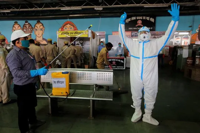 Railway officer Vasudev Pandey sanitizes railway workers after a train of migrant laborers from Gujarat state arrived in their home state in Prayagraj, India, Wednesday, May 6, 2020. India is running train service for thousands of migrant workers desperate to return home since it imposed a nationwide lockdown to control the spread of the coronavirus. (Photo by Rajesh Kumar Singh/AP Photo)