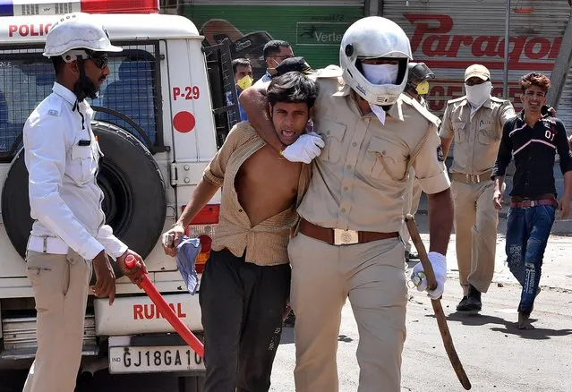 Gujarat police personnel detain stranded migrant workers during a protest demanding Gujarat's government travelling arrangements to return to their homes during nationwide lockdown as a preventive measure against COVID-19 coronavirus, in Surat, some 270 kms from Ahmedabad on May 4, 2020. (Photo by Reuters/Stringer)
