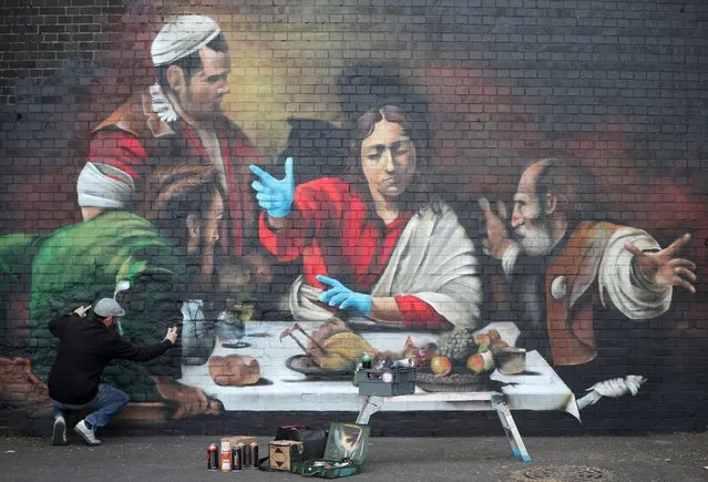 Artist Lionel Stanhope paints a mural in Ladywell depicting the Supper at Emmaus by Caravaggio with added protective gloves, following the outbreak of the coronavirus disease (COVID-19), London, Britain, May 5, 2020. (Photo by Hannah McKay/Reuters)