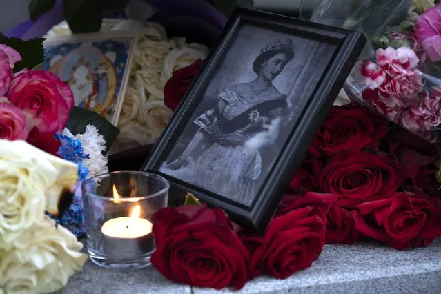 A portrait of Queen Elizabeth II, a candle and flowers in remembrance of her Majesty are seen at the Embassy of the United Kingdom in Moscow, Russia, Friday, September 9, 2022. Queen Elizabeth II, Britain's longest-reigning monarch and a rock of stability across much of a turbulent century, died Thursday after 70 years on the throne. She was 96. (Photo by Dmitry Serebryakov/AP Photo)