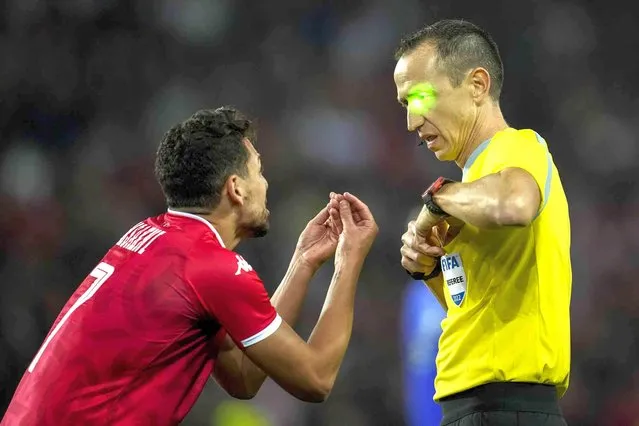 Referee Ruddy Buquet has a green laser light pointed to his face as he talks with Tunisia's Youssef Msakni during the international friendly soccer match between Brazil and Tunisia at the Parc des Princes stadium in Paris, France, Tuesday, September 27, 2022. (Photo by Christophe Ena/AP Photo)