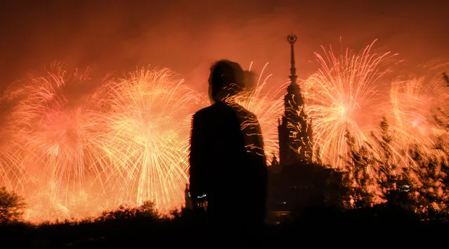 A girl watches fireworks exploding behind the Moscow State University in Moscow on June 24, 2020 during celebrations marking the 75th anniversary of the Soviet victory over Nazi Germany in World War Two. (Photo by Alexander Nemenov/AFP Photo)