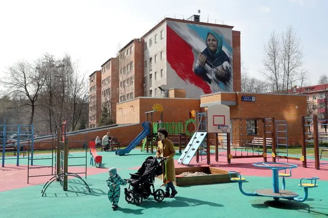 A woman with a stroller walks on a playground in front of an apartment block with a patriotic mural by Russian artist Ilya Demchinko in support of the “special military operation” in Ukraine, the town of Reutov, outside Moscow, Russia 25 April 2022. Russian troops on 24 February had entered Ukrainian territory resulting in fighting and destruction in the country, a huge flow of refugees, and multiple sanctions against Russia. (Photo by Maxim Shipenkov/EPA/EFE)