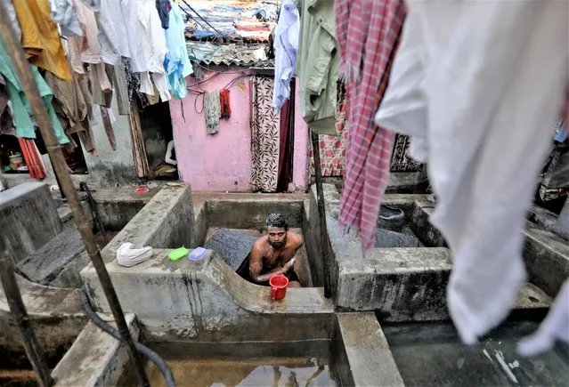 A laundryman bathes in a concrete wash pen at the Dhobi Ghat open air laundry in Mumbai, India on November 24, 2022. (Photo by Niharika Kulkarni/Reuters)