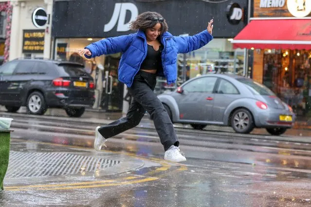 A woman jumps over a large puddle of rainwater in north London on October 23, 2022. The Met Office has issued a yellow weather warning for for heavy rain and thunderstorm in some parts of South East England for today. (Photo by Dinendra Haria/London News Pictures)