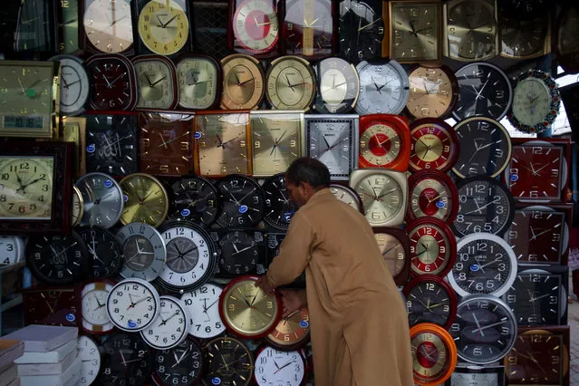 A Pakistani vendor adjusts a wall clock displayed at his stall for sale at a weekly bazaar in Islamabad, Pakistan, Sunday, October 19, 2014. (Photo by Anjum Naveed/AP Photo)