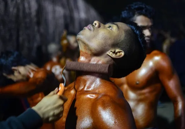 This photograph taken on January 2, 2018 shows an Indian bodybuilding competitor getting a tanning product applied to his body ahead of the All Assam Body Building and Fitness Competition 2018 in Dibrugarh in India's northeast Assam state. The participants use tanning products and oil to increase definition to show off their muscles for the competition. (Photo by AFP Photo/Stringer)