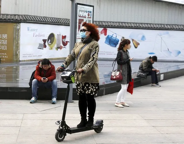 A woman wearing a mask rides an electronic scooter on a hazy day at a business district in Beijing April 10,  2015. (Photo by Kim Kyung-Hoon/Reuters)