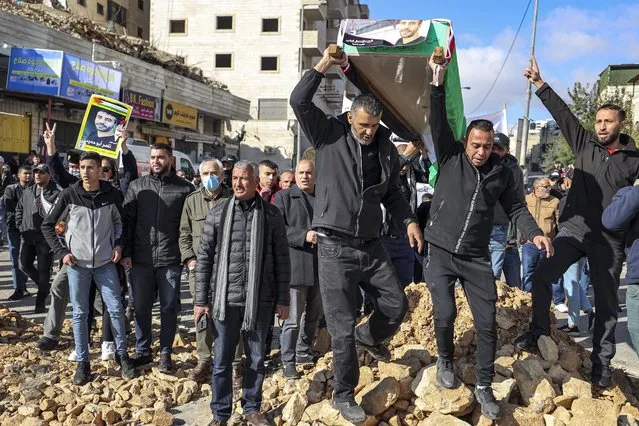Men carry a symbolic coffin draped in a Palestinian flag during a demonstration demanding the return of the bodies of Palestinian being held by Israel, at the Qalandia checkpoint south of Ramallah in the occupied West Bank on December 27, 2022. (Photo by Abbas Momani/AFP Photo)