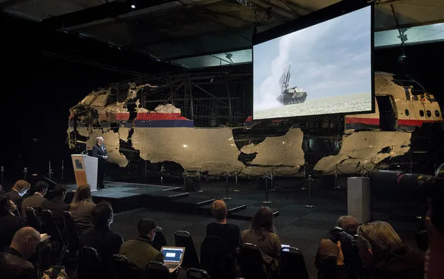 A video show the launch of a BUK missile, while a part of the reconstructed forward section of the fuselage is displayed behind, as Tjibbe Joustra, left, head of the Dutch Safety Board presents the board's final report into what caused Malaysia Airlines Flight 17 to break up high over Eastern Ukraine last year, killing all 298 people on board, during a press conference in Gilze-Rijen, central Netherlands, Tuesday, October 13, 2015. (Photo by Peter Dejong/AP Photo)