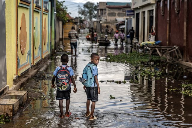 Two students carry their school bags as they walk through a flooded residential area on their way to school, where rising waters from Lake Tanganyika have inundated homes in the Kinyinya III neighborhood of Gatumba, on May 9, 2025. Water levels at lakes in East Africa are rising alarmingly fast. The effects of climate change have worsened the floods of Africa's second-largest lake, often preventing the Ruzizi River from flowing into it. Lake Tanganyika has been above its normal level since 2018 and has been displacing people for years. (Photo by Luis Tato/AFP Photo)