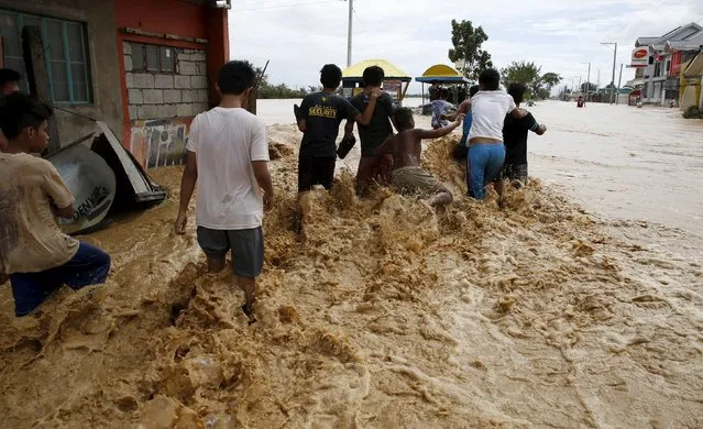 Residents wade along a flooded road amidst a strong current in Sta Rosa, Nueva Ecija in northern Philippines October 19, 2015, after it was hit by Typhoon Koppu. (Photo by Erik De Castro/Reuters)