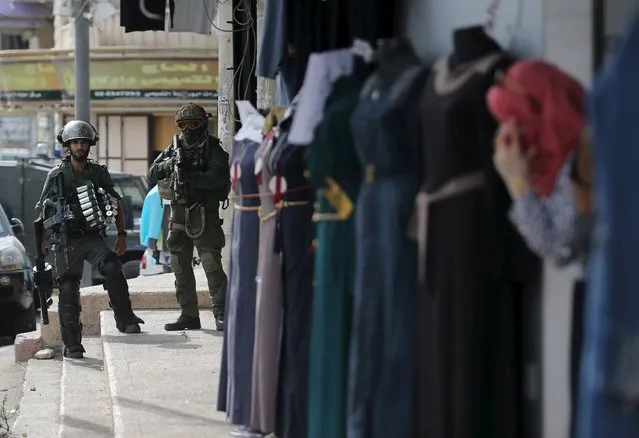 Israeli border policemen take position as a Palestinian woman looks out a shop during clashes in the West Bank town of Al-Ram, near Jerusalem October 22, 2015. (Photo by Mohamad Torokman/Reuters)