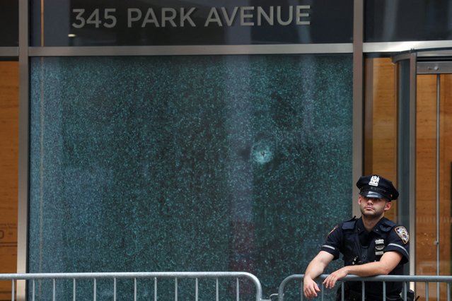 A police officer stands next to the glass window with a bullet hole near the scene of a deadly mass shooting in Manhattan, New York City, on July 29, 2025. (Photo by Mike Segar/Reuters)