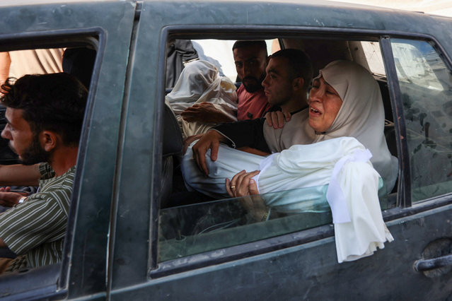 A Palestinian woman mourns as she holds the shrouded body of a young relative, killed in an Israeli strike, before the funeral procession at Al-Shifa hospital in Gaza City on July 9, 2025. (Photo by Omar Al-Qattaa/AFP Photo)