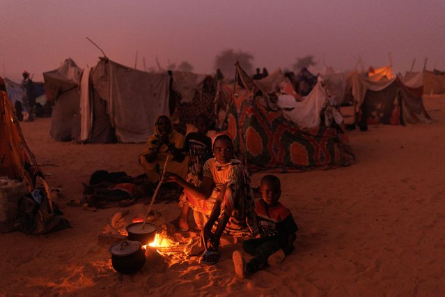 Newly arrived Sudanese refugees cook food over fires outside their makeshift shelters at twilight close to a relocation camp on April 24, 2024 near Adre, Chad. Since the beginning of the recent conflict between the paramilitary Rapid Support Forces (RSF) and the the Sudanese Armed Forces, (SAF), which began in March 2023, over 600,000 new refugees have crossed the border from Darfur in Sudan, into Chad. The total number of refugees, including those from previous conflicts, now stands at 1.2 million. Aid agencies, including The World Food Programme, (WFP), Médecins Sans Frontières (MSF) and the United Nations High Commissioner for Refugees, (UNHCR), already struggling with acute supply shortages, have warned that the life-saving programmes in Chad, will “grind to a halt in a matter of weeks without urgent funding”. Chad is now home to one of the largest and fastest-growing refugee populations in Africa. (Photo by Dan Kitwood/Getty Images)