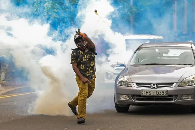 An anti-government demonstrator throws back a tear gas canister fired by police during a protest demanding the release of Inter University Students' Federation leader Wasantha Mudalige, outside the United Nations (UN) office in Colombo on January 16, 2023. (Photo by Ishara S. Kodikara/AFP Photo)