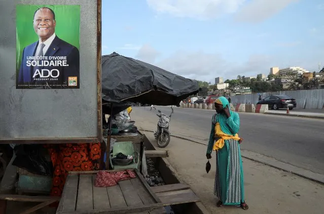 A woman stands near a campaign poster of a presidential candidate Alassane Ouattara of the ruling RHDP coalition, in Attecoube district, Abidjan, Ivory Coast on October 23, 2020. (Photo by Luc Gnago/Reuters)
