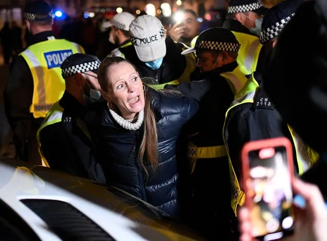 A woman is detained by police from “The Million Mask March”, an annual event described as a march “against austerity, the infringement of rights, war crimes, corrupt politicians and to reinstate liberty”, gather in Trafalgar Square in central London, Thursday, November 5, 2020. The march was taking place on the same day national lockdown rules come into force as Britain joined large swathes of Europe in a coronavirus lockdown designed to save its health care system from being overwhelmed. Pubs, along with restaurants, hairdressers and shops selling non-essential items closed on Thursday until at least Dec. 2. (Photo by Alberto Pezzali/AP Photo)