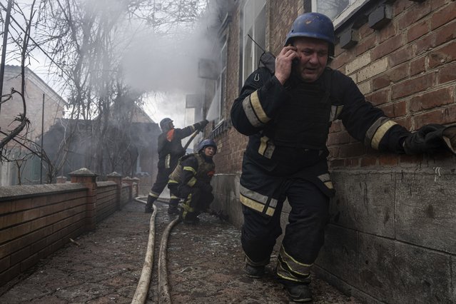 A rescue worker speaks on the phone while his team puts out a fire in a house which was shelled by Russian forces at the residential neighbourhood in Kostiantynivka, Ukraine on Friday, March 10, 2023. (Photo by Evgeniy Maloletka/AP Photo)