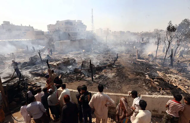 People search for their belongings amid the debris of their houses after a large fire broke out destroying over 100 homes in a slum area in Karachi, Pakistan, 05 November 2015. According to reports a fire destroyed more than 100 domiciles in the Junejo slum town area of Mehmoodabad in Karachi. The cause of the fire has yet to be identified. (Photo by Rehan Khan/EPA)