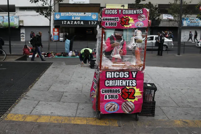 A vendor, wearing a protective face mask, is bundled up against the cold as she prepares churros in her mobile stall in Mexico City, Wednesday, November 18, 2020, amid the new cornavirus pandemic. Mexico on Saturday topped 1 million registered COVID-19 cases and nearly 100,000 test-confirmed deaths, though officials agree the number is probably much higher. (Photo by Rebecca Blackwell/AP Photo)