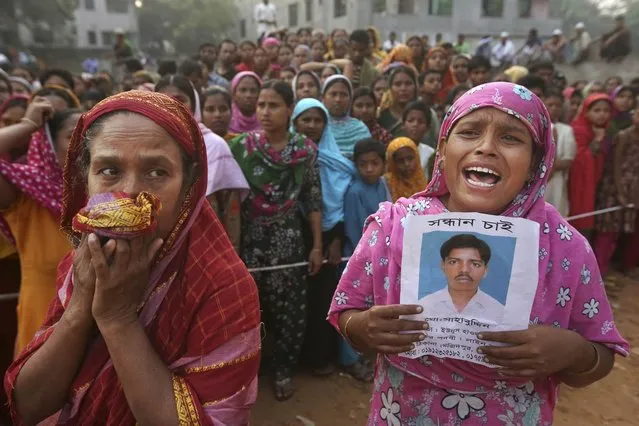 A Bangladeshi woman weeps as she holds a picture of her and her missing husband as she waits at the site of a building that collapsed Wednesday in Savar, near Dhaka, Bangladesh, Friday, April 26, 2013. The death toll reached hundreds of people as rescuers continued to search for injured and missing, after a huge section of an eight-story building that housed several garment factories splintered into a pile of concrete. (Photo by Kevin Frayer/AP Photo)