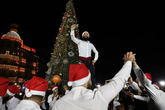 A band performs a folkloric dance around a Christmas tree in the Lebanon's capital Beirut's Martyr square on November 24, 2022. (Photo by Anwar Amro/AFP Photo)